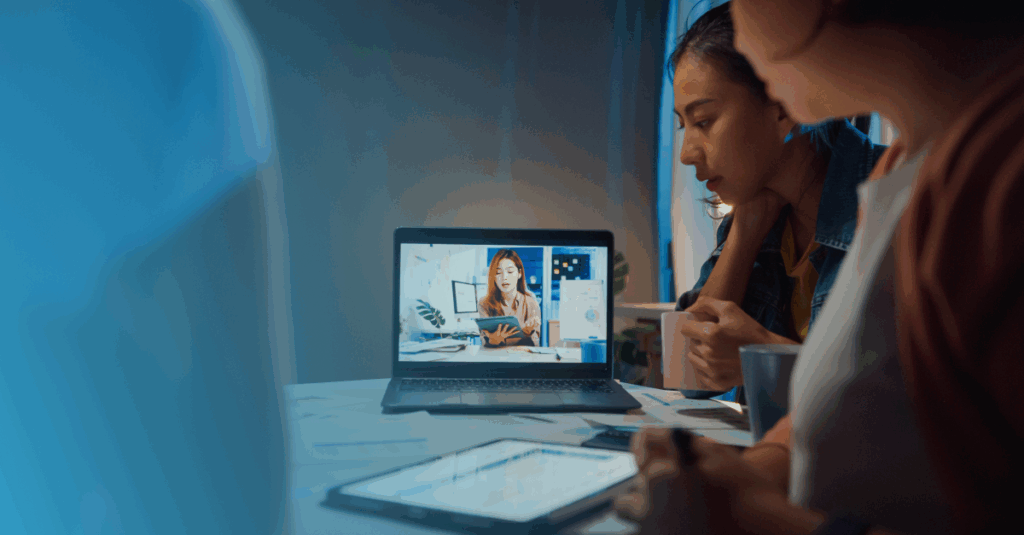 Two professionals collaborating at a desk in a hybrid work setup.